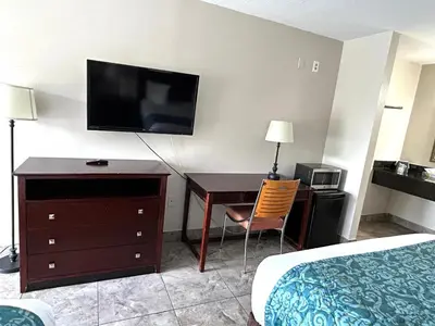 a hotel room with a desk and a flat screen tv at Shining Light Inn & Suites in Kissimmee