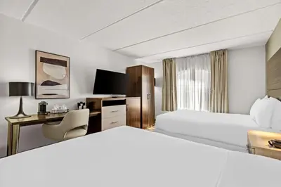 a white hotel room with a bed and a desk at Sonesta Essential Orlando Airport in Orlando