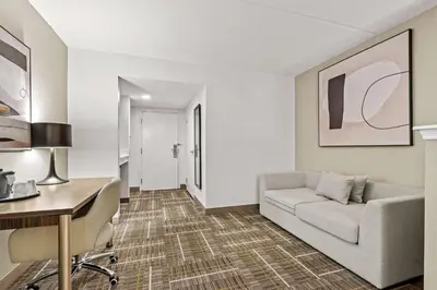 a living room with a couch and a desk at Sonesta Essential Orlando Airport in Orlando