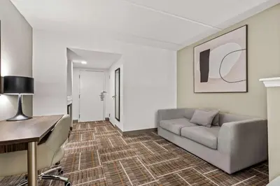 a living room with a couch and a desk at Sonesta Essential Orlando Airport in Orlando