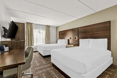 a hotel room with two beds and a desk at Sonesta Essential Orlando Airport in Orlando