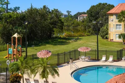 a pool at a resort with chairs and umbrellas at Parc Corniche Condominium Suites in Orlando