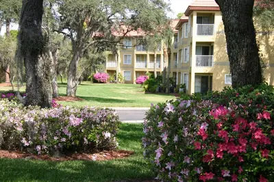 a building with flowers in front of a yard at Parc Corniche Condominium Suites in Orlando