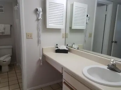 a bathroom with a sink and a mirror and a toilet at Parc Corniche Condominium Suites in Orlando