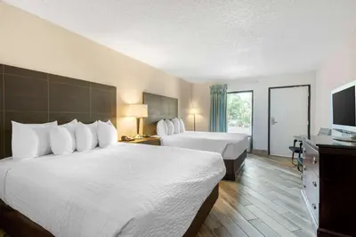 a hotel room with two beds and a flat screen tv at Clarion Inn & Suites Kissimmee-Lake Buena Vista South in Kissimmee