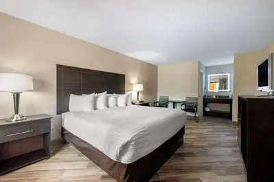 a hotel room with a large bed and a desk at Clarion Inn & Suites Kissimmee-Lake Buena Vista South in Kissimmee