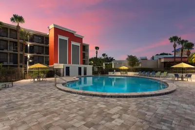 a swimming pool with tables and chairs in front of a building at Days Inn by Wyndham Orlando Conv. Center/International Dr in Orlando