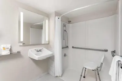 a white bathroom with a sink and a shower at Days Inn by Wyndham Orlando Conv. Center/International Dr in Orlando