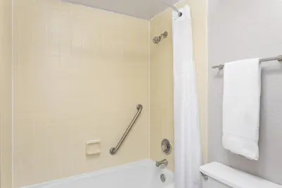 a bathroom with a tub and a shower with a towel at Days Inn by Wyndham Orlando Conv. Center/International Dr in Orlando
