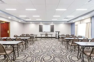 a conference room with tables and chairs and a screen at Wingate by Wyndham, Universal Studios - Free Theme Park Shuttle in Orlando