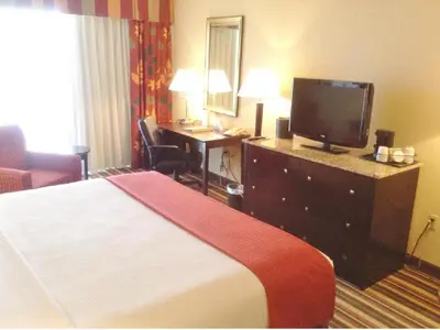 a hotel room with a bed and a desk with a television at Holiday Inn & Suites Orlando SW - Celebration Area by IHG in Orlando