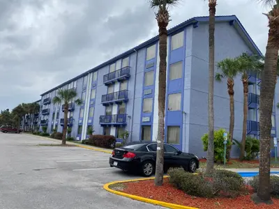 a car parked in front of a building with palm trees at Monumental Movieland Hotel in Orlando