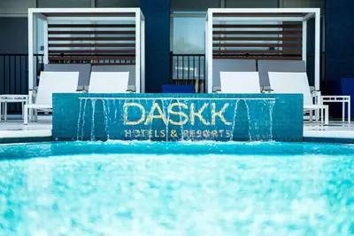 a swimming pool with white chairs and a blue wall at DASKK Orlando Hotel near Universal Blvd, an Ascend Collection Hotel in Orlando