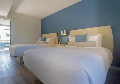 two beds in a hotel room with blue walls at DASKK Orlando Hotel near Universal Blvd, an Ascend Collection Hotel in Orlando