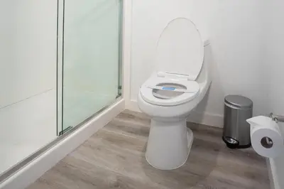 a bathroom with a toilet and a glass shower at DASKK Orlando Hotel near Universal Blvd, an Ascend Collection Hotel in Orlando