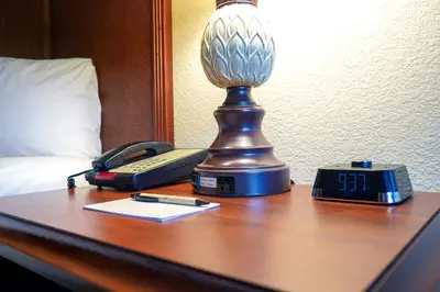a desk with a lamp and a phone on a bed at Rosen Inn International Near The Parks in Orlando