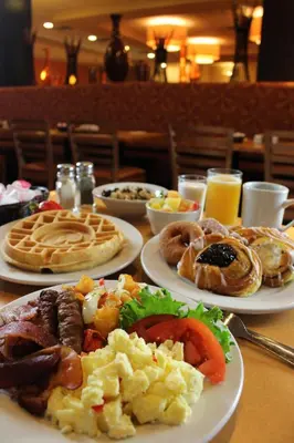 a table with plates of breakfast foods and drinks at Rosen Inn International Near The Parks in Orlando