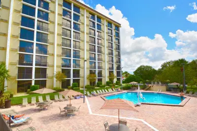 a large building with a pool and tables and chairs at Rosen Inn Closest to Universal in Orlando