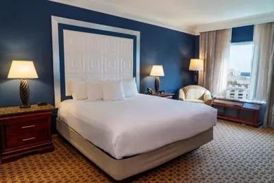 a hotel room with a large bed and a chair at Rosen Plaza Hotel Orlando Convention Center in Orlando