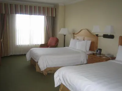a hotel room with two beds and a chair and a window at Monumental Hotel Orlando in Orlando