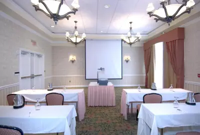 a conference room with white tables and a screen at Monumental Hotel Orlando in Orlando