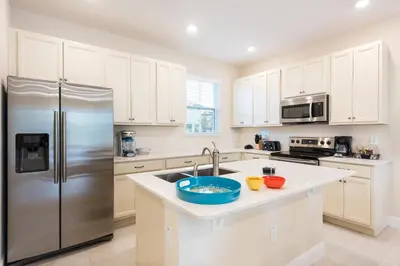 a kitchen with white cabinets and a stainless steel refrigerator at Cannon Thunder Cottage With Private Hot Tub Near Disney With Margaritaville Resort & Island H2O Access - 3066Pi in Orlando
