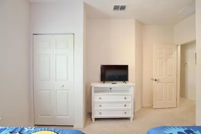 a bedroom with a white dresser with a tv on it at Amazing private townhouse in gated community with amenities Great location, near Disney! in Kissimmee