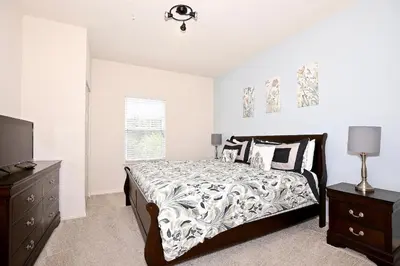 a bedroom with a bed and a dresser and a television at 3 Bedroom townhouse fits 8, 10' to Disney parks! in Kissimmee