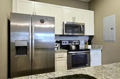 a kitchen with a stainless steel refrigerator and microwave at Luxury 3 bedroom townhouse, comfortable sleeps 8 Super close to Disney! in Kissimmee