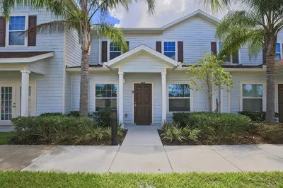 a white house with palm trees in front of it at Luxury 3 bedroom townhouse, comfortable sleeps 8 Super close to Disney! in Kissimmee
