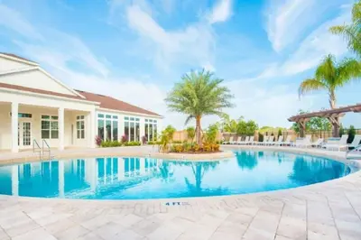 a swimming pool with palm trees and a house at Fantastic Townhouse in Lux community sleeps 8, 10' to Disney!! in Kissimmee