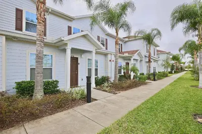 a row of houses with palm trees and a sidewalk at Fantastic Townhouse in Lux community sleeps 8, 10' to Disney!! in Kissimmee