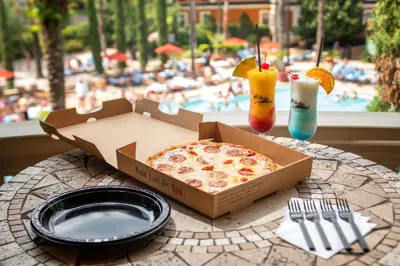 a pizza in a box sitting on a table with a plate at Floridays Orlando Two & Three Bed Rooms Condo Resort in Orlando
