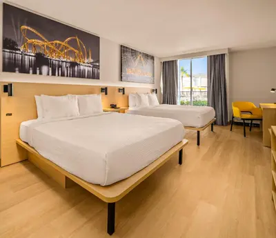 a hotel room with two beds and a table at B&B HOTEL Orlando International Drive near Universal - Newly Renovated! in Orlando
