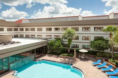 an exterior view of a hotel with a swimming pool at Sheraton Suites Orlando Airport Hotel in Orlando