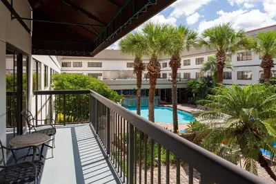 a balcony with a pool and palm trees at Sheraton Suites Orlando Airport Hotel in Orlando