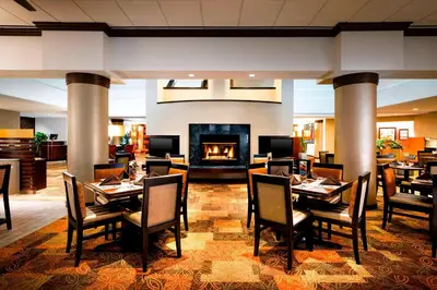 a restaurant with tables and chairs and a fireplace at Sheraton Suites Orlando Airport Hotel in Orlando