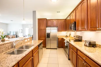 a kitchen with wooden cabinets and a stainless steel refrigerator at Vista Cay at Epic Universe - Luxury 4 bedroom condo in Orlando