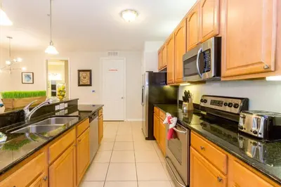 a kitchen with wooden cabinets and stainless steel appliances at Vista Cay at Epic Universe - Luxury 3 bedroom condo in Orlando