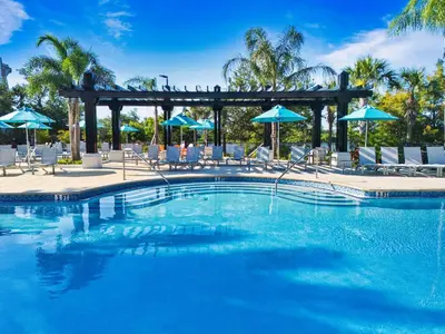 a large swimming pool with chairs and umbrellas at Vista Cay at Epic Universe - Luxury Lakeview 4 bedroom condo in Orlando