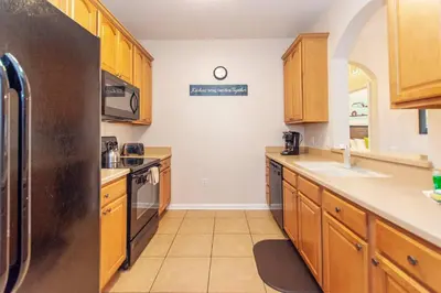 a kitchen with wooden cabinets and a stainless steel refrigerator at Vista Cay at Epic Universe - Standard 3 bedroom condo in Orlando