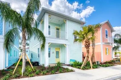 a blue house with palm trees in front of it at Sea Breeze Cottage Near Disney With Private Hot Tub & Margaritaville Resort & Island H20 Waterpark Access - 3016Sr in Orlando