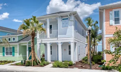 a white house with a porch and palm trees at Premium Cottage With Private Hot Tub Near Disney Margaritaville Resort & Island H2O Access - 3025La in Orlando