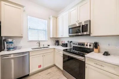 a kitchen with white cabinets and stainless steel appliances at Premium Cottage With Private Hot Tub Near Disney Margaritaville Resort & Island H2O Access - 3025La in Orlando