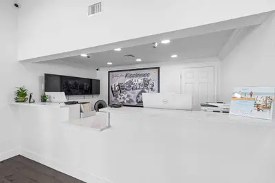 a white room with a white counter and a poster at Super 8 by Wyndham Kissimmee-Orlando in Kissimmee