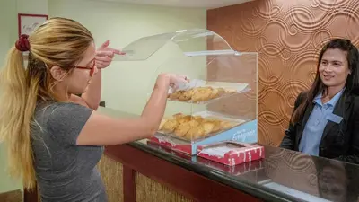 a woman pointing at a display case of donuts at Galleria Palms Orlando - Free Theme Park Shuttles in Orlando