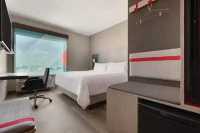 a bedroom with a bed and a desk and a window at avid hotels - Orlando International Airport by IHG in Orlando