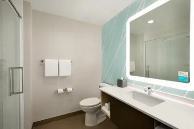 a bathroom with a sink and a toilet and a mirror at avid hotels - Orlando International Airport by IHG in Orlando