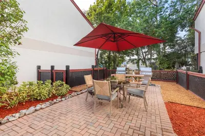 a patio with a table and chairs and a red umbrella at Bryan's Spanish Cove in Orlando