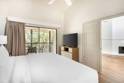 a white bedroom with a large bed and a television at Bryan's Spanish Cove in Orlando